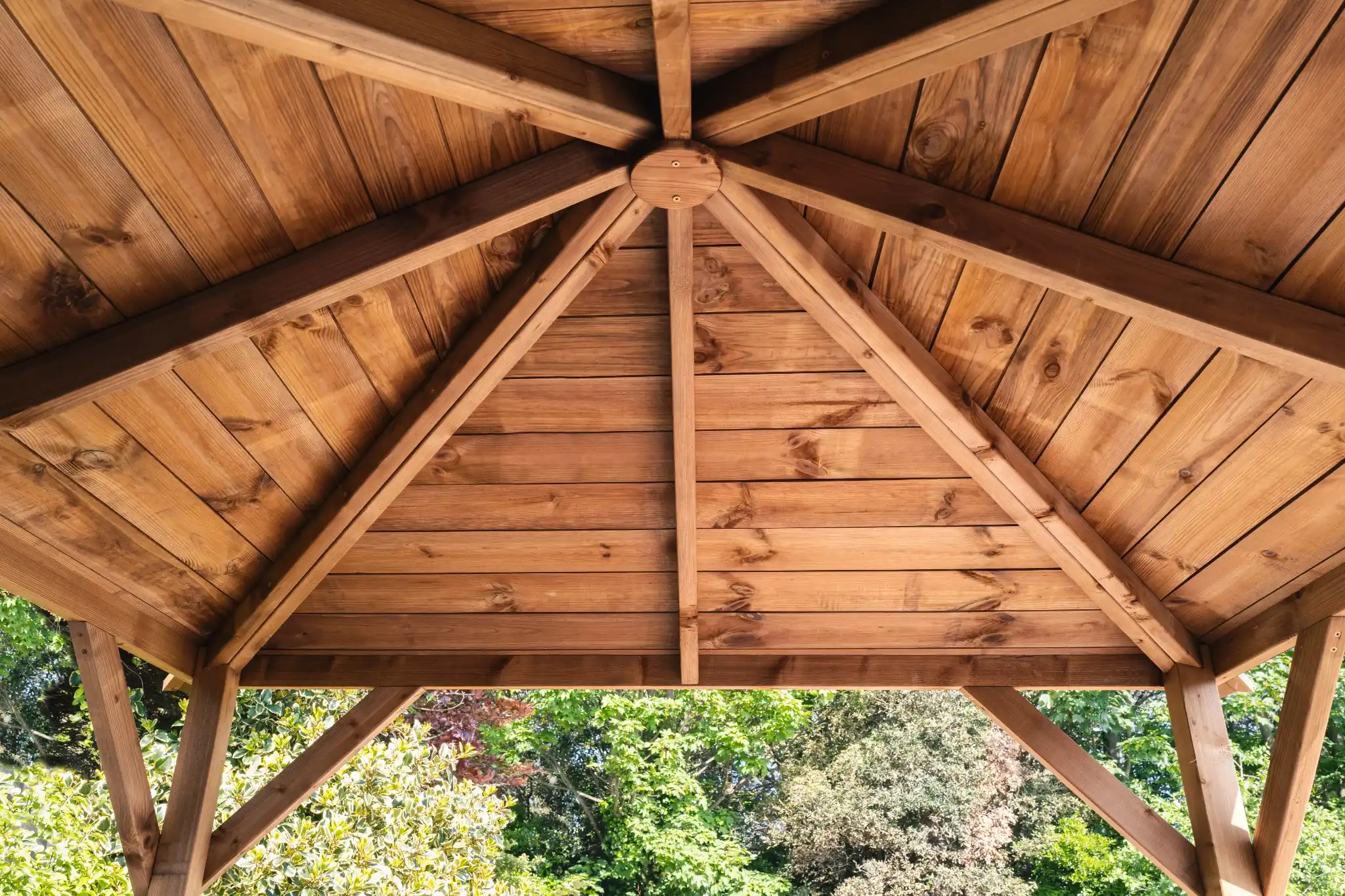Structure en bois élégante et couverte, offrant un espace ombragé en plein air avec un toit en bois détaillé et entourée de verdure