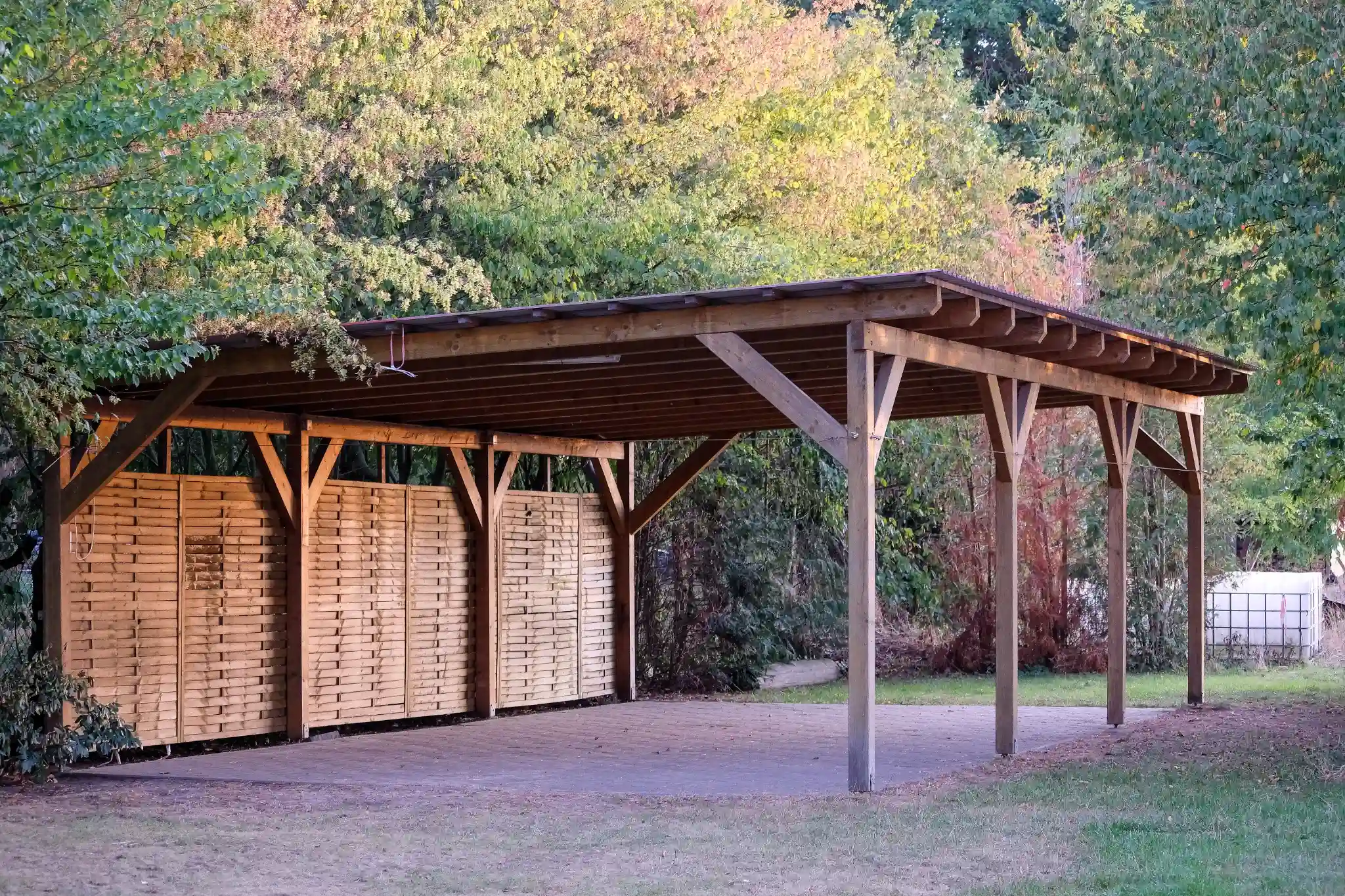 Abri de voiture en bois dans un cadre naturel, avec une structure robuste et un design ouvert qui s'intègre parfaitement à l'environnement environnant